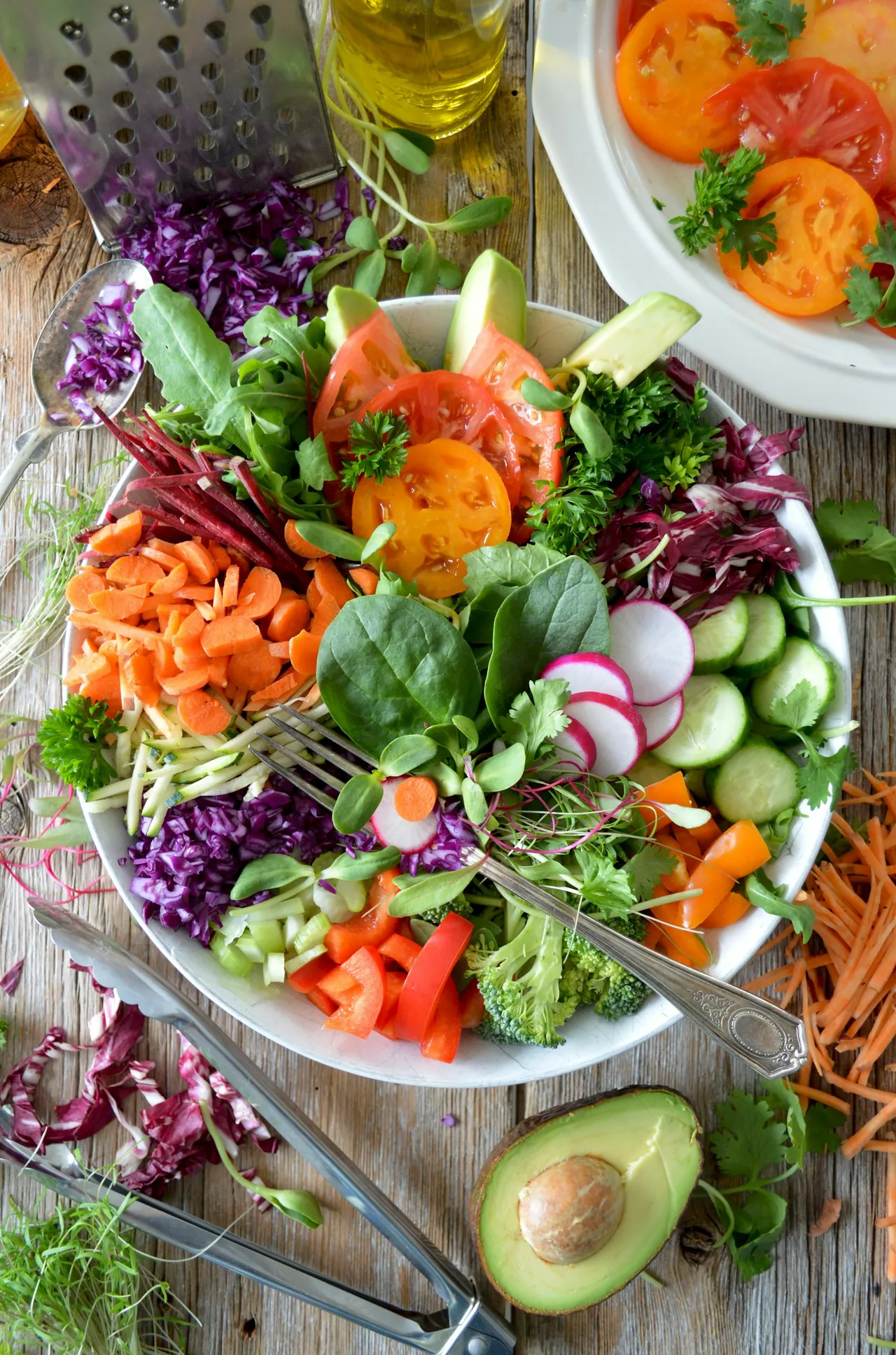 An overhead view of a bowl of mixed salad with carrots, radishes, tomatoes, cucumber and leafy greens